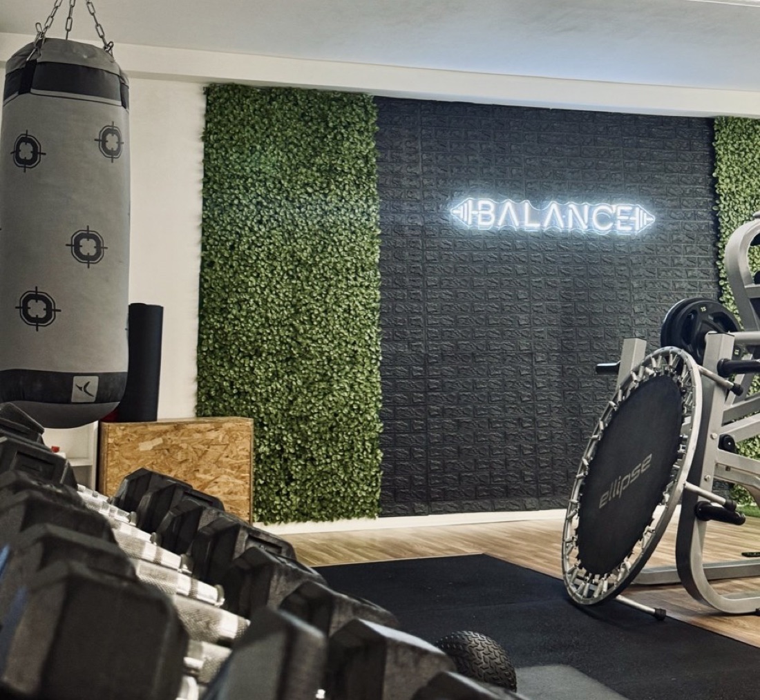 Zona de pesos com o néon Balance, saco de boxe e halteres